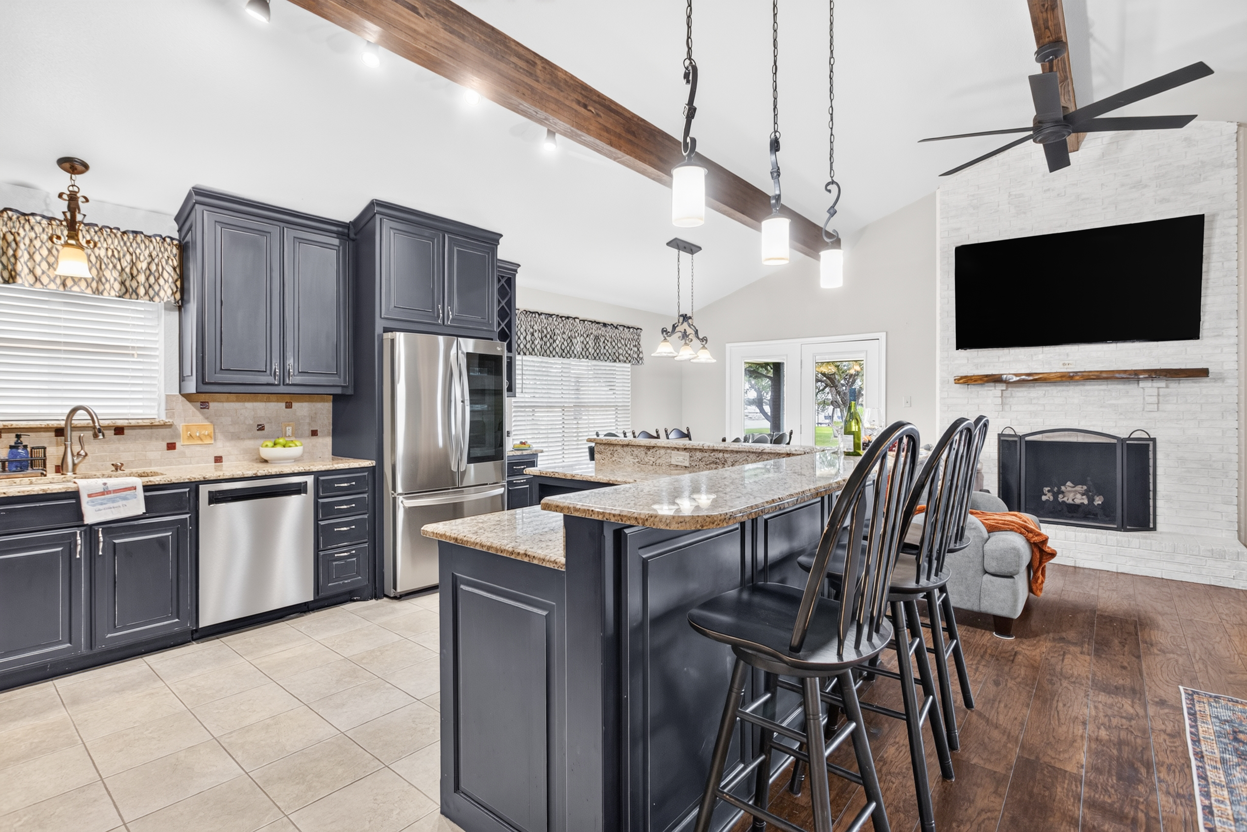 Spacious vaulted kitchen with island seating, fireplace, and TV