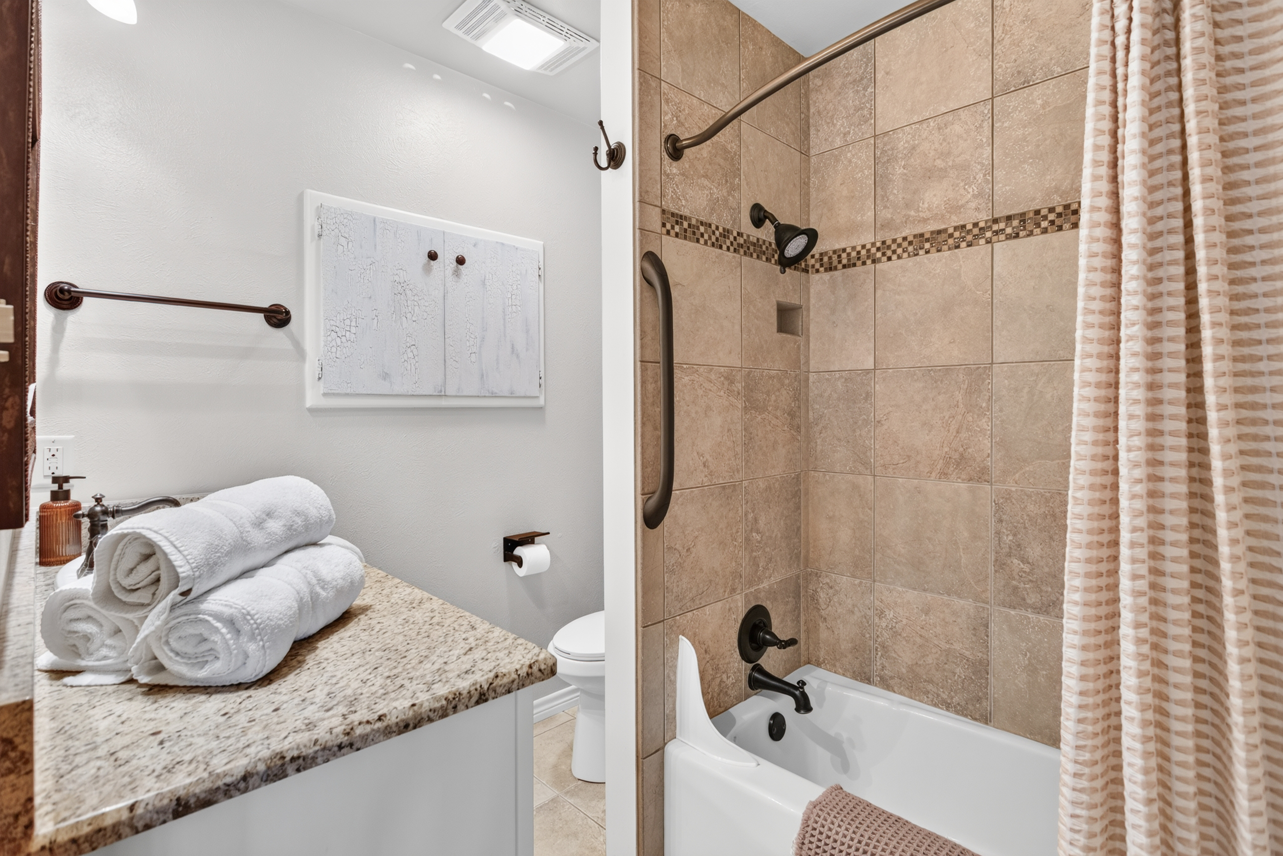 Bright tiled bathroom with granite vanity and tub-shower combo