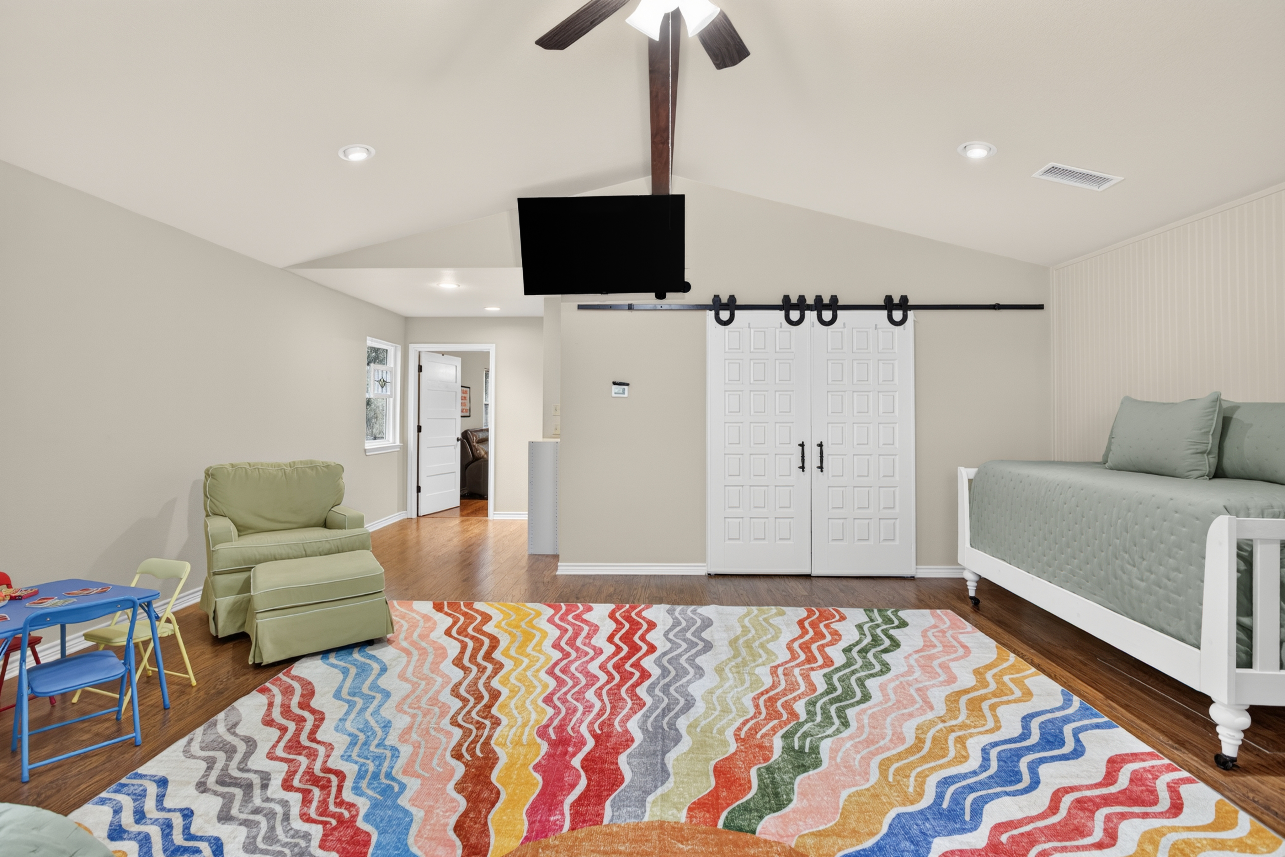 Spacious family-friendly loft bedroom with TV, daybed, and colorful rug