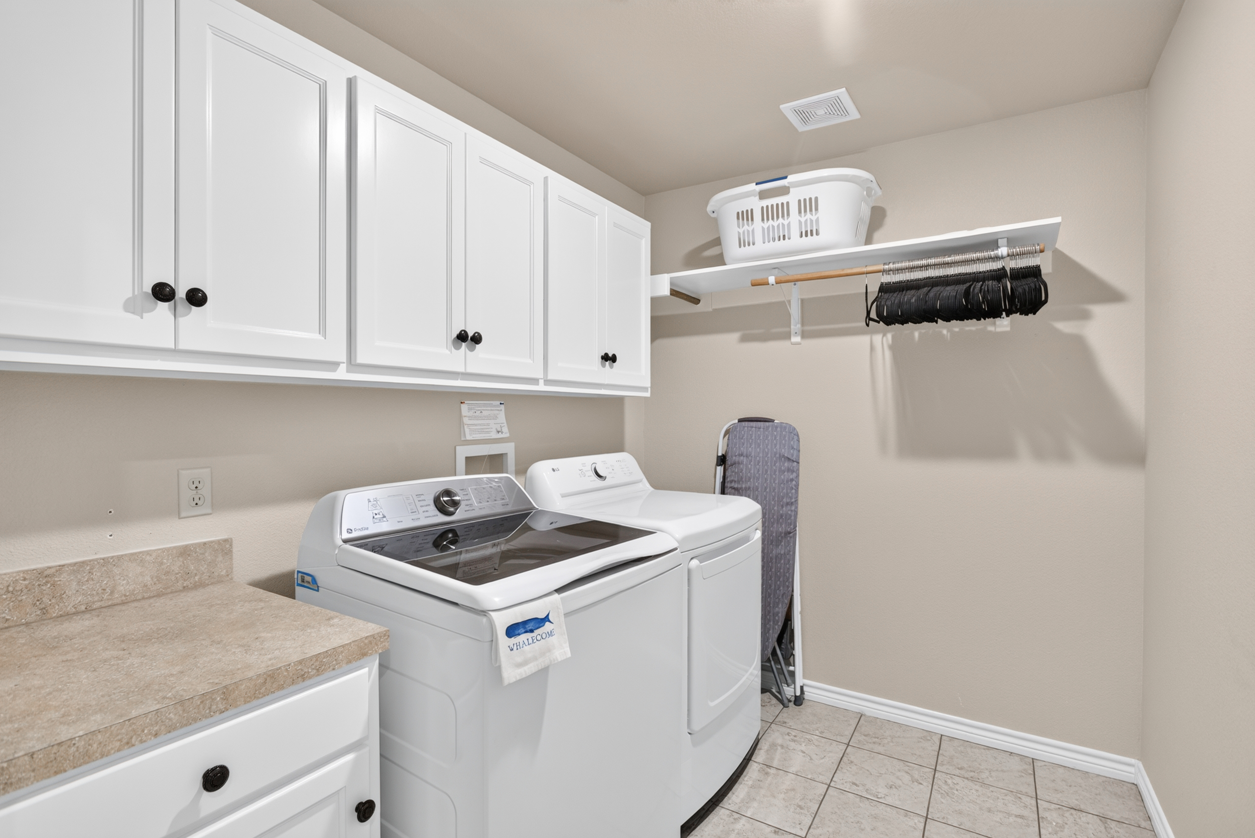 Spacious laundry room with washer/dryer, storage, and folding space