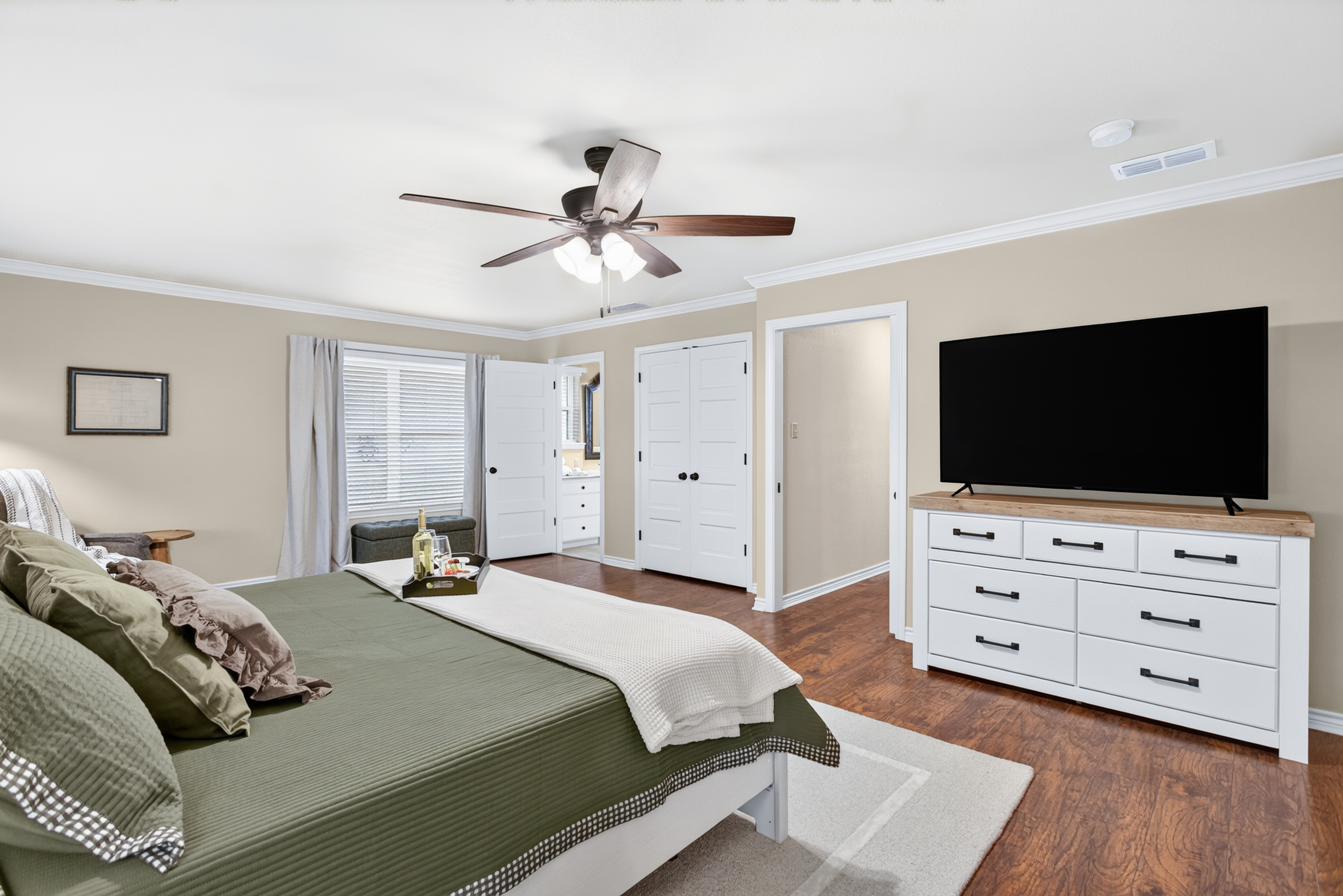 Spacious, serene bedroom with a king bed, big TV, and warm natural light