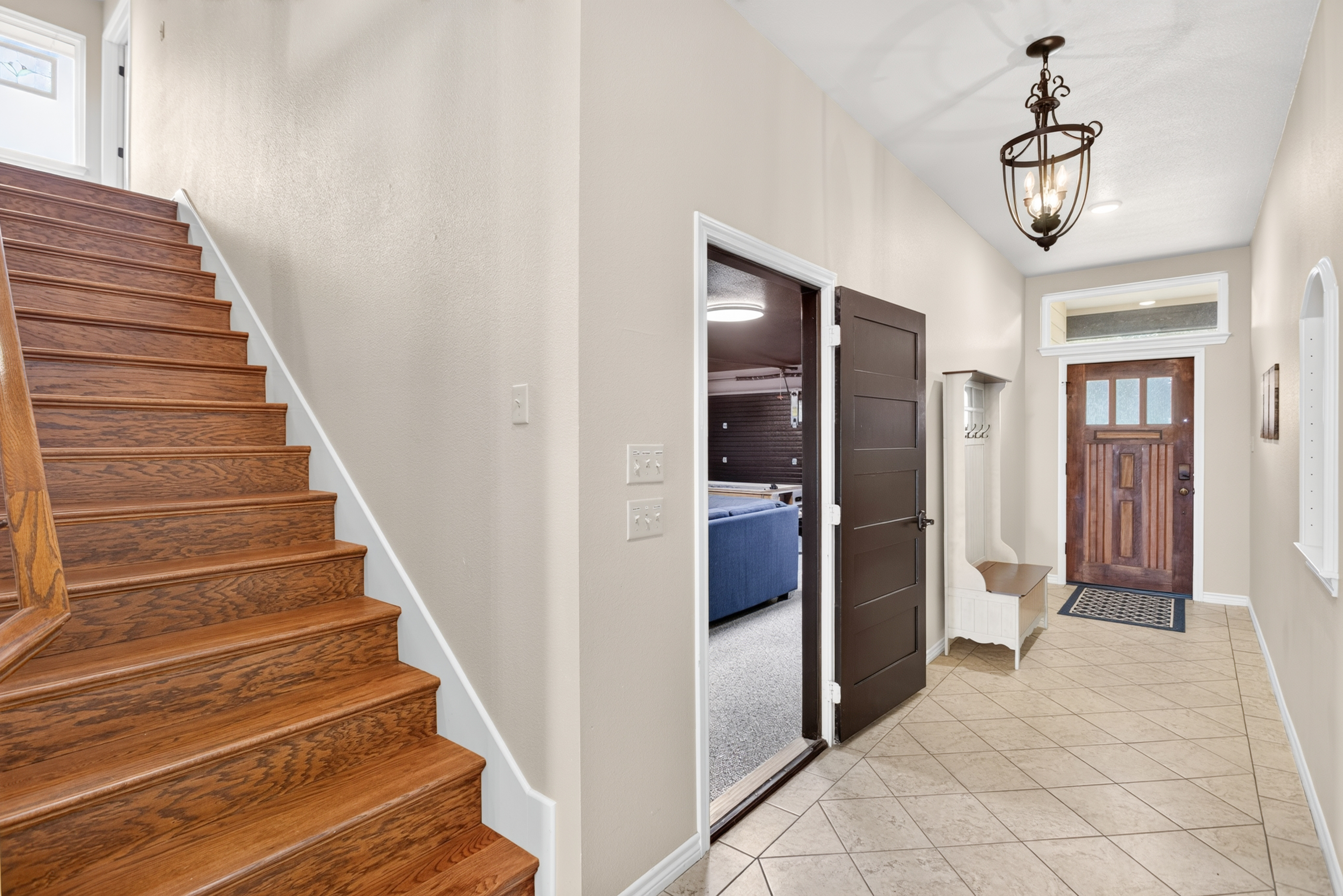 Bright entryway with wood stairs, high ceilings, and stylish foyer seating
