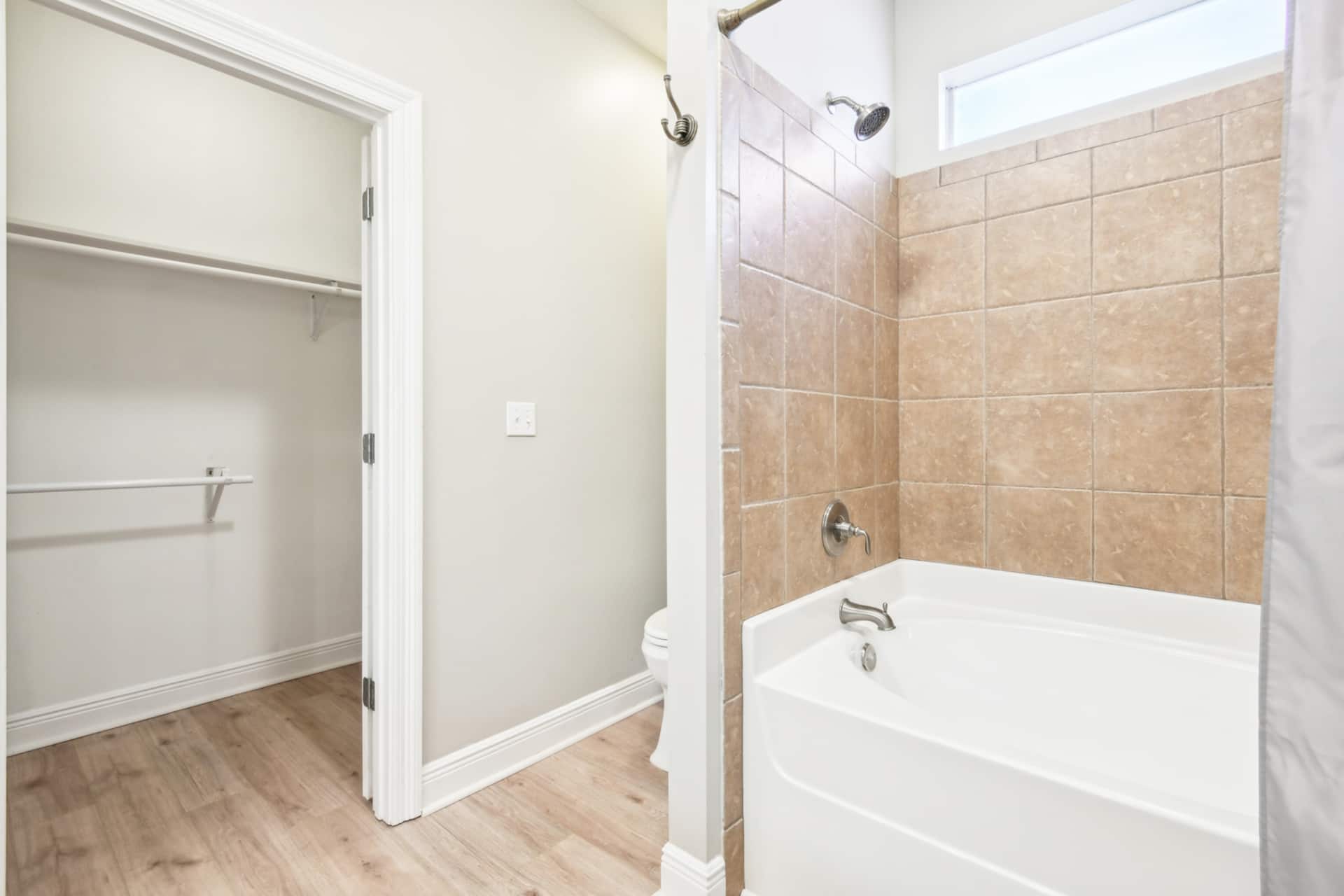 Bright bathroom with tiled tub-shower and spacious walk-in closet