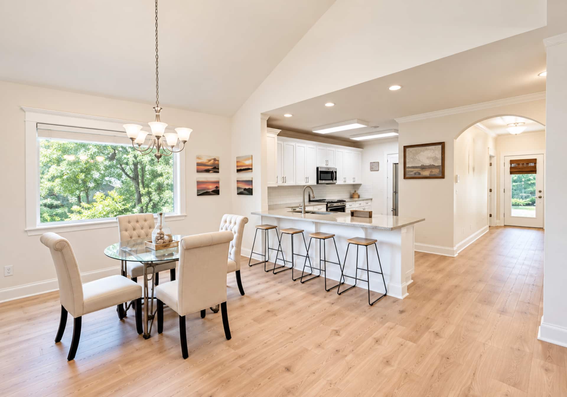 Bright open dining area with breakfast bar, vaulted ceilings, and garden views
