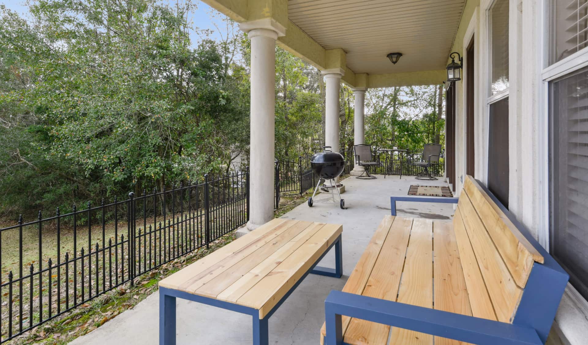Spacious covered porch with grill, seating, and peaceful wooded views