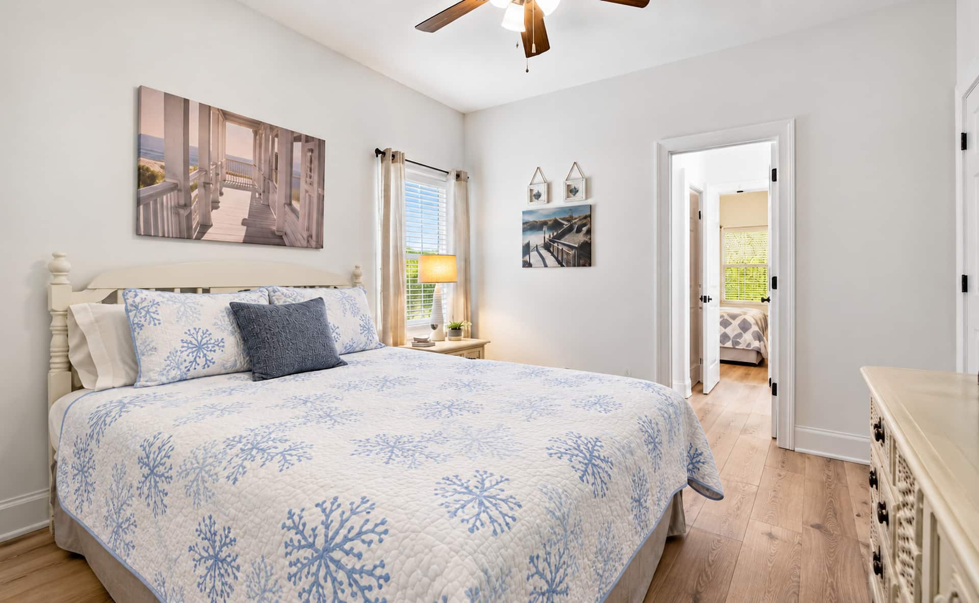 Bright coastal bedroom with airy decor, ceiling fan, and serene style