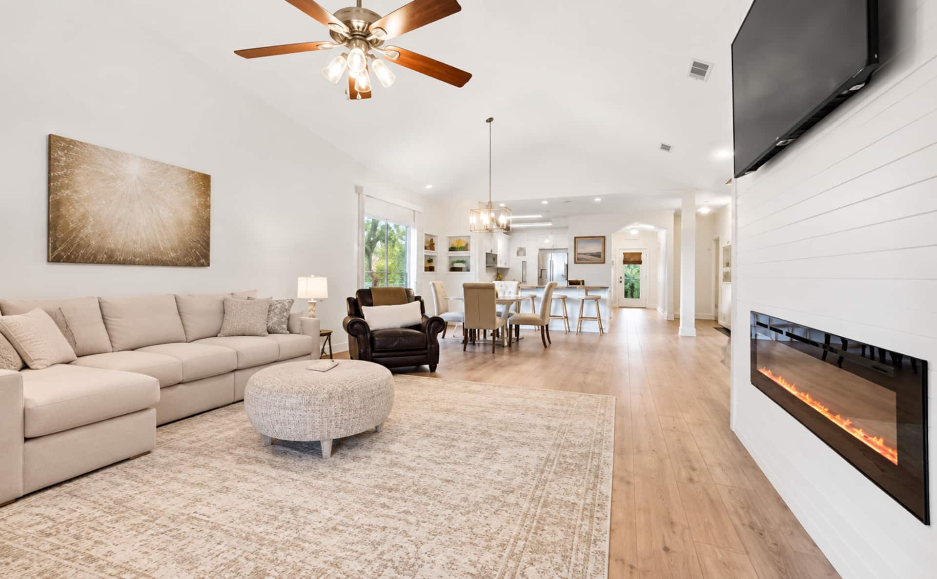 Bright open-concept living with fireplace, big TV, and stylish dining area