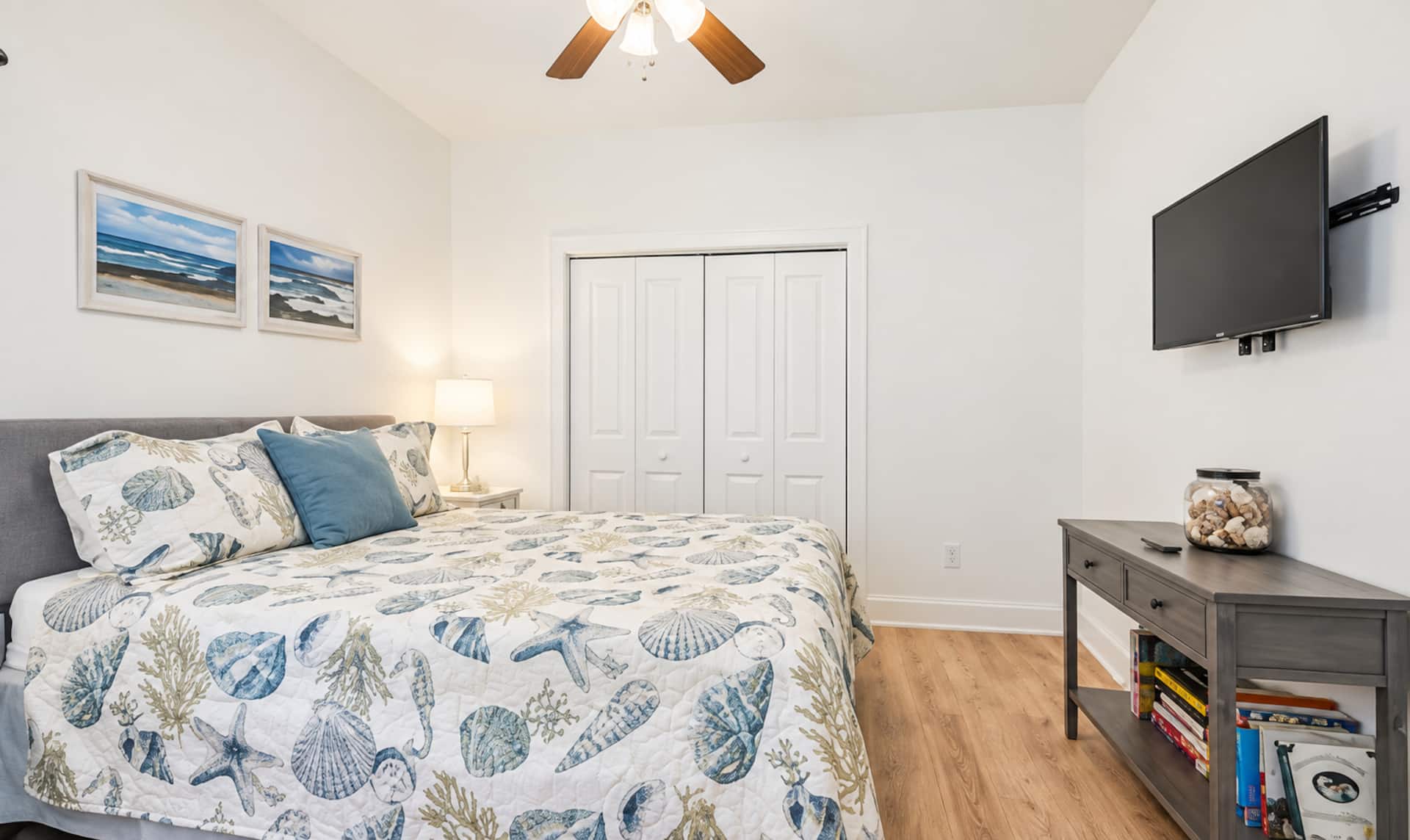 Bright coastal bedroom with TV, closet, and beach-inspired decor