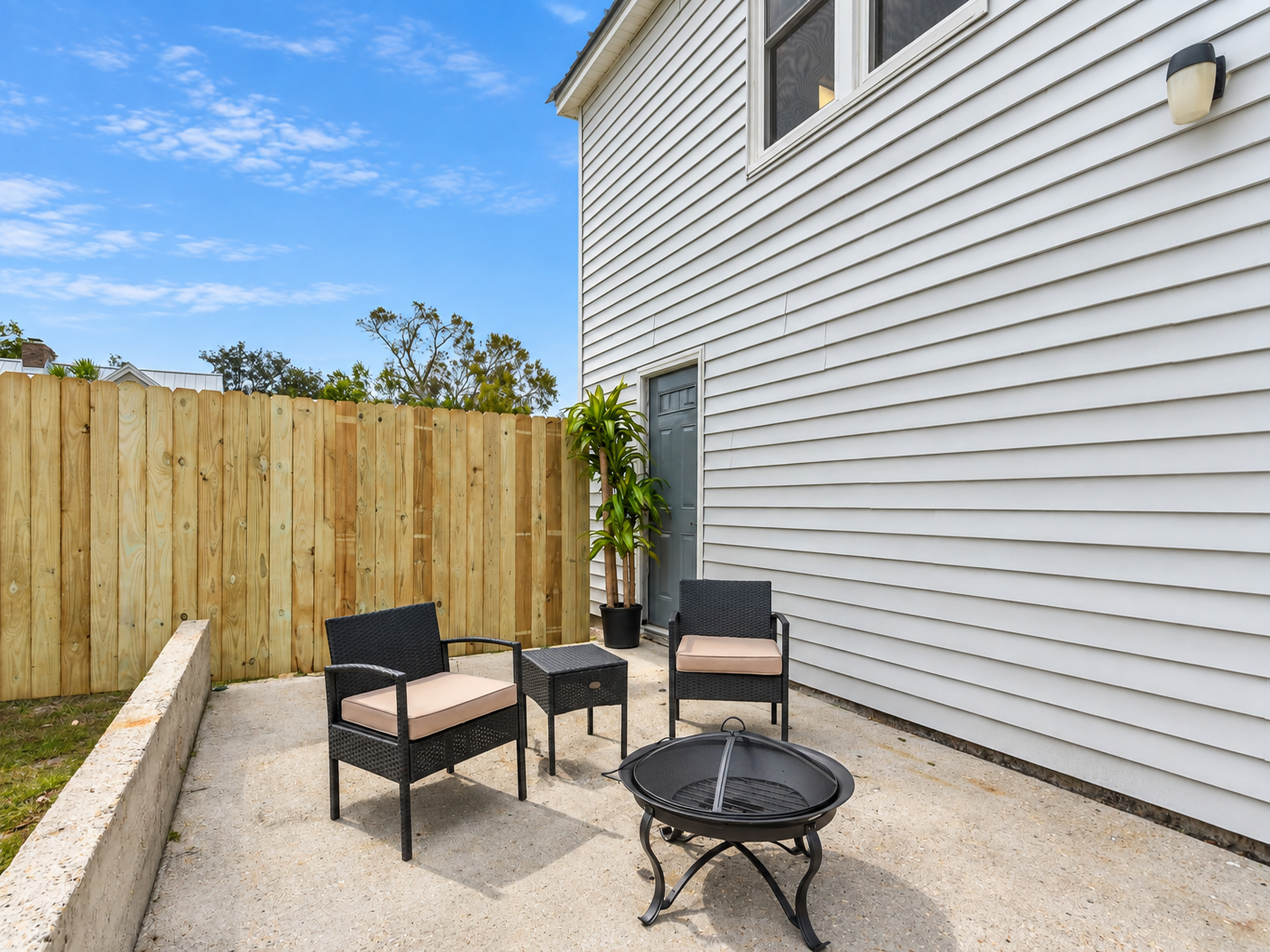 Private fenced patio with cozy seating and fire pit for outdoor relaxation