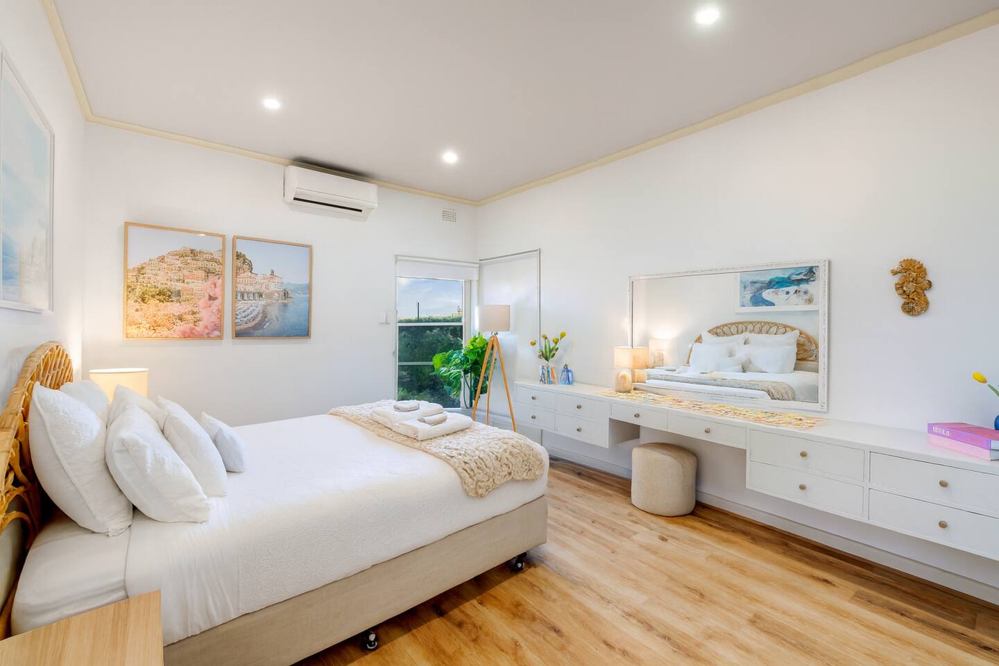 Sunlit bedroom with coastal artwork and built-in vanity