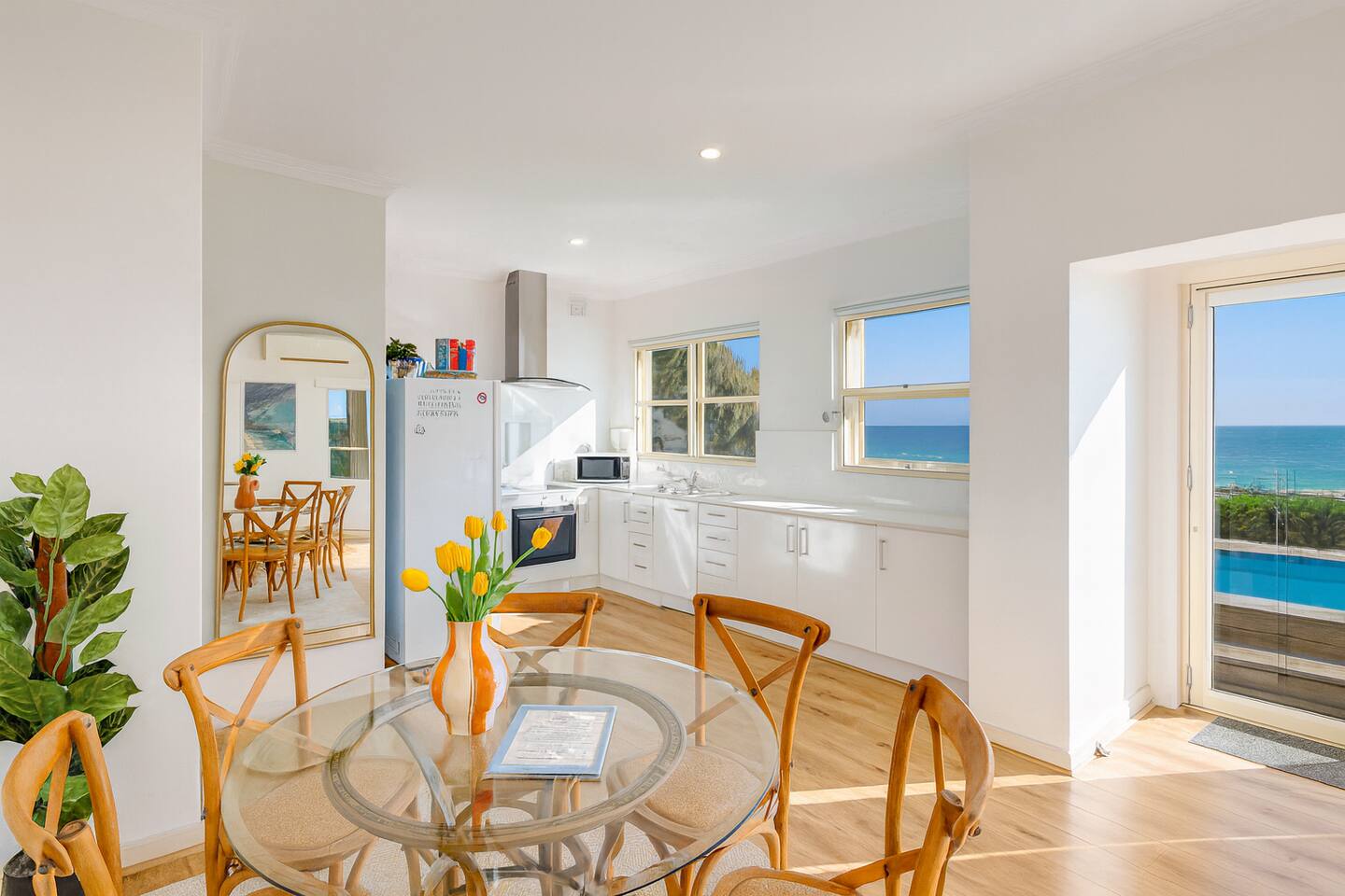 Glass-top dining table with ocean views through the open doorway