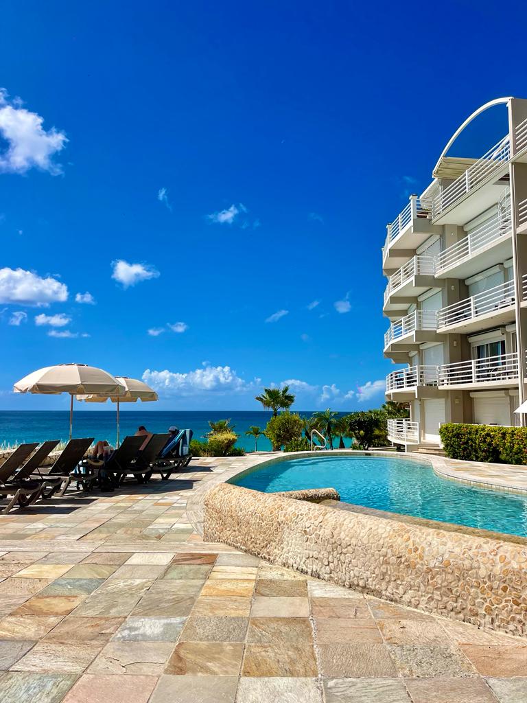 Oceanfront pool deck with loungers, balconies, and stunning sea views