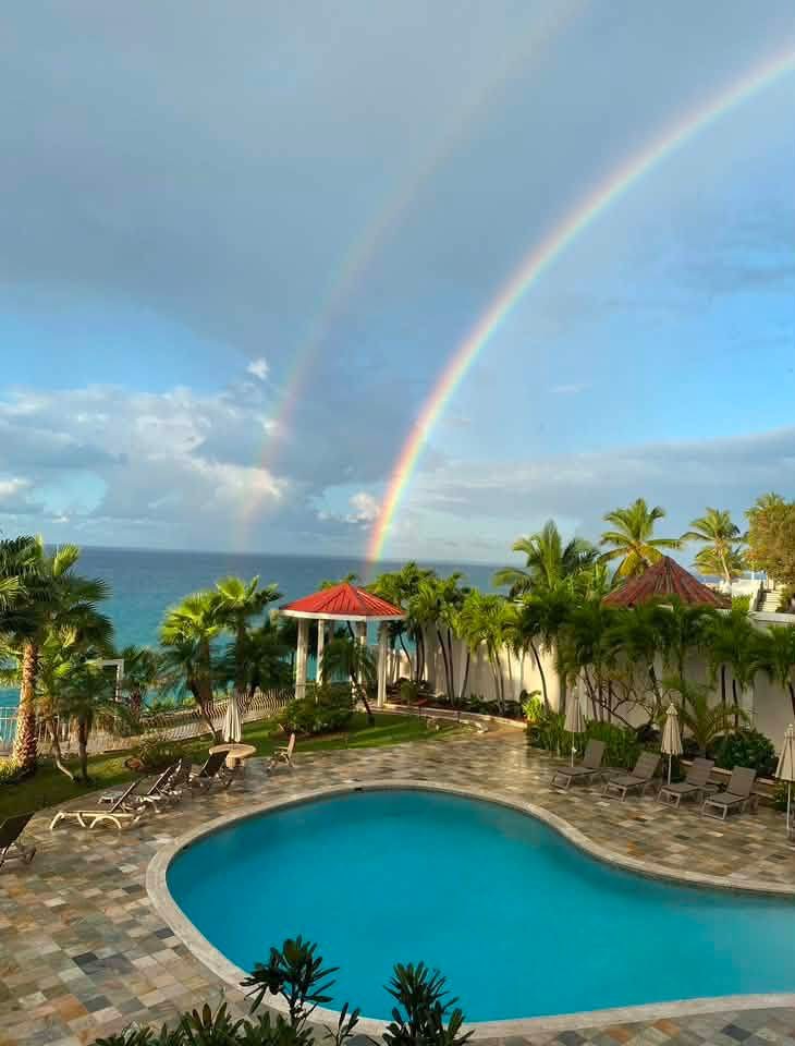 Oceanfront pool oasis with tropical palms and a stunning double rainbow