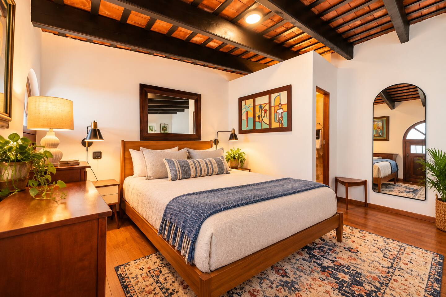 A cozy retreat upstairs! This loft Queen bedroom combines beautiful exposed wooden beams, warm wood furnishings, and colorful Puerto Rican artwork. The airy layout includes convenient access to a private en-suite half bath.