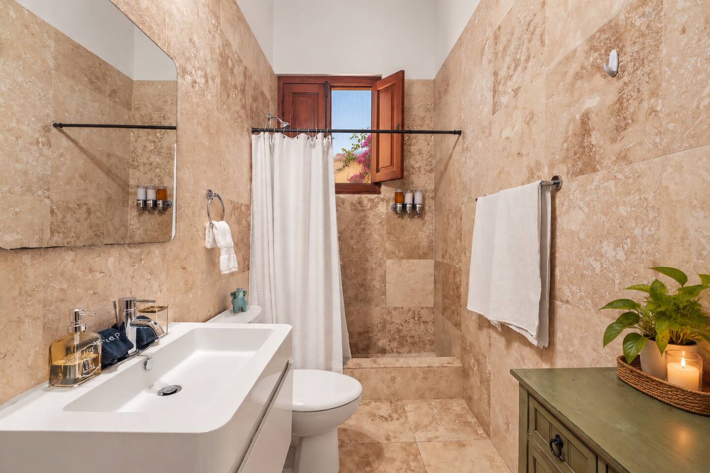Relax in this charming, fully stocked bathroom featuring natural stone tile and a walk-in shower. We provide shampoo, conditioner, body wash, a hair dryer, fresh towels, washcloths, and dedicated makeup removal towels for your convenience.