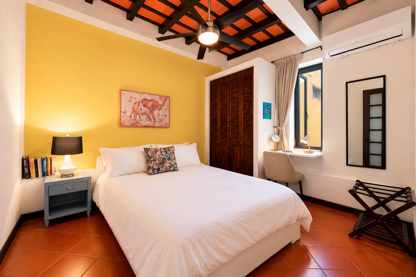 Unwind in this bright, inviting bedroom featuring a comfortable bed, quiet AC, ceiling fan, & charming exposed-beam ceilings. A dedicated workspace doubles as a makeup station, while warm Caribbean colors and thoughtful touches make you feel at home.