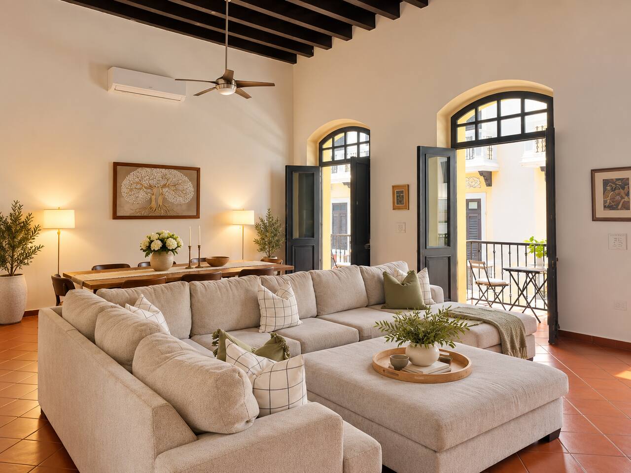 Relax in the spacious living room with soaring ceilings, exposed wood beams, plush sectional seating, and A/C. French doors open to charming balconies overlooking Old San Juan’s colorful streets, and the adjoining dining area is perfect for gathering
