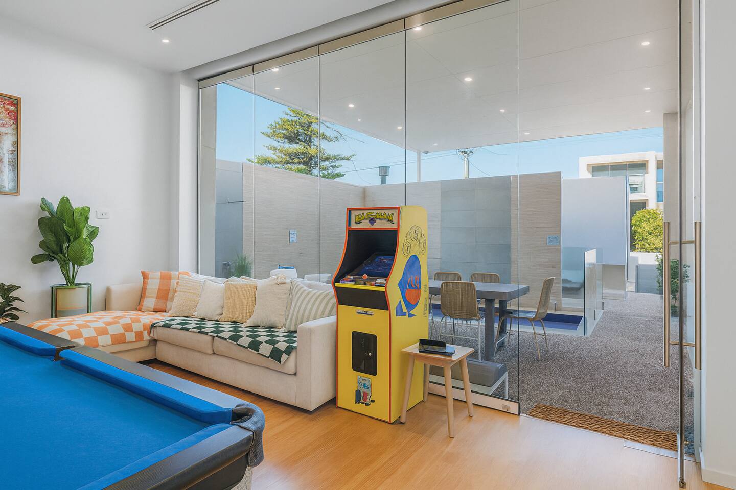 Sun-drenched recreation room with pool table and arcade machine